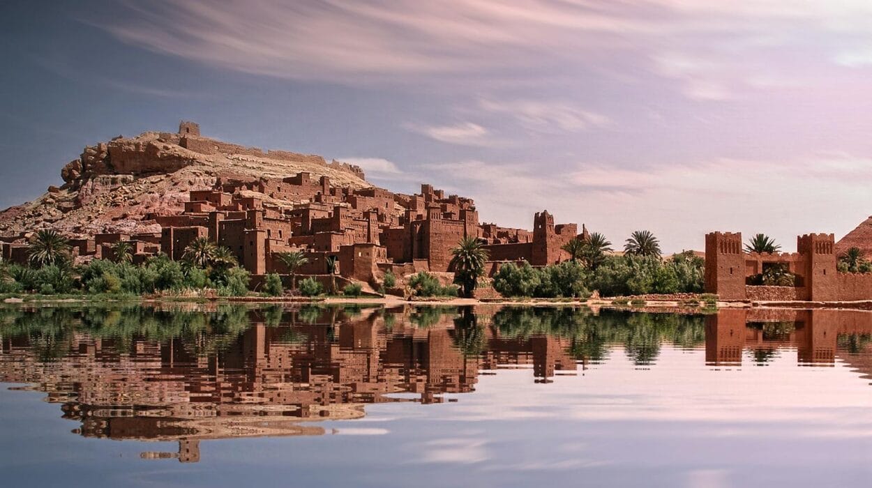 Picturesque reflection of Ouarzazate's historic ksar by the river under a vibrant sky.